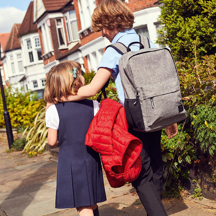 Boy and girl wearing M&S school uniform with boy wearing pale grey school rucksack