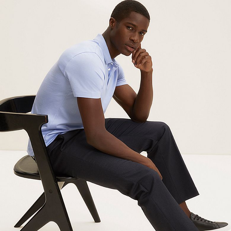 Man wearing pale blue polo shirt, tailored navy trousers and black trainers