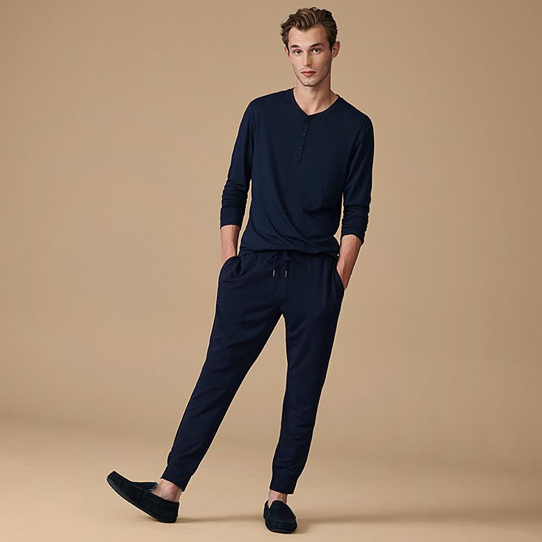 Man wearing navy top, navy joggers and slippers