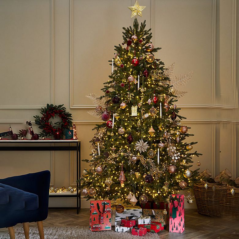  Grand Fir Christmas tree with decoration and wrapped presents in a room with a navy velvet chair. Shop Christmas trees
