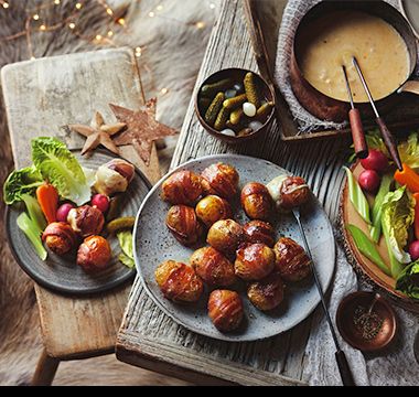 Truffle cheddar fondue with potatoes in blankets and cornichons. See the recipe