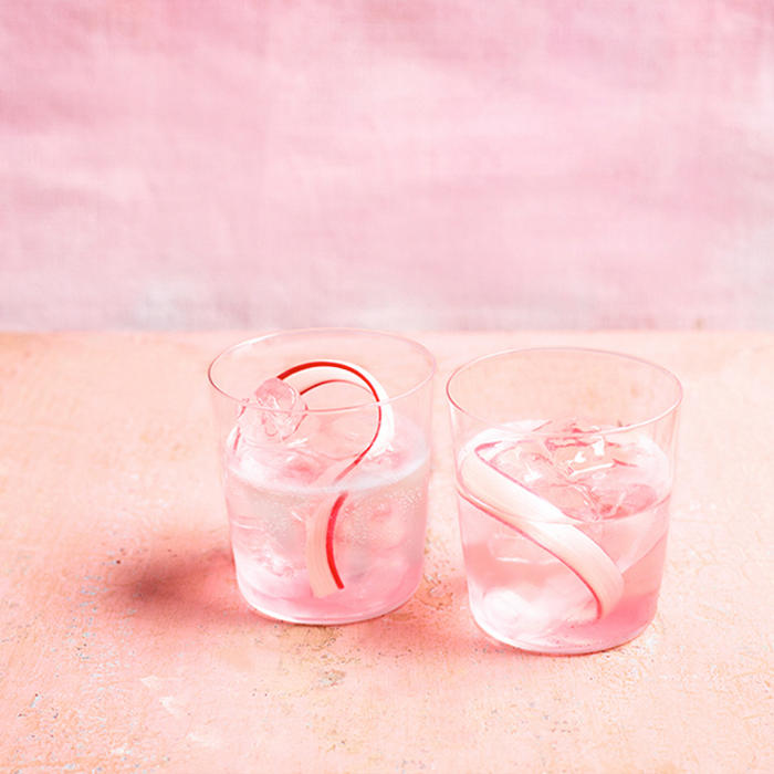 Two glasses of pink rhubarb gin cocktail with rhubarb ribbon garnish