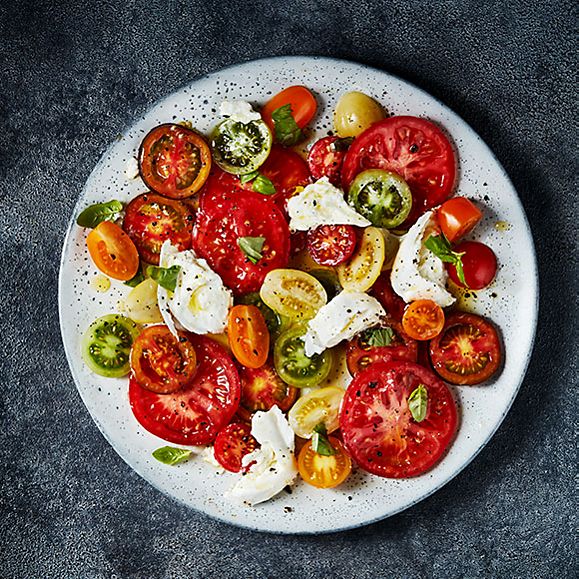 A plate of sliced M&S Isle of Wight tomatoes with buffalo mozzarella, basil and olive oil