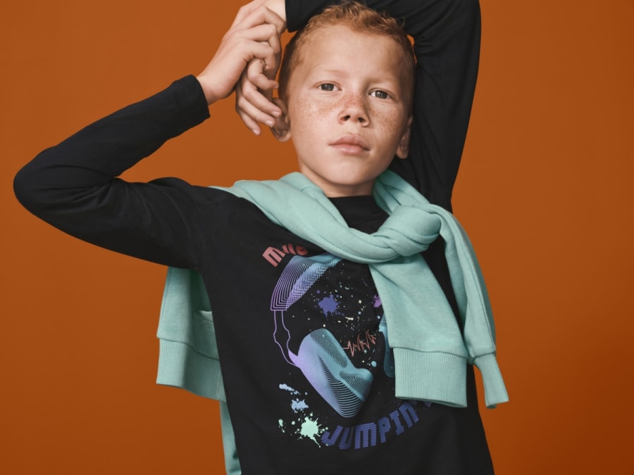 Boy wearing a graphic print top. Shop kidswear