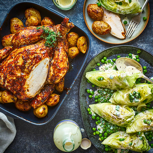 Tom Kerridge's juiciest whole BBQ roasted chicken sat on roasted new potatoes