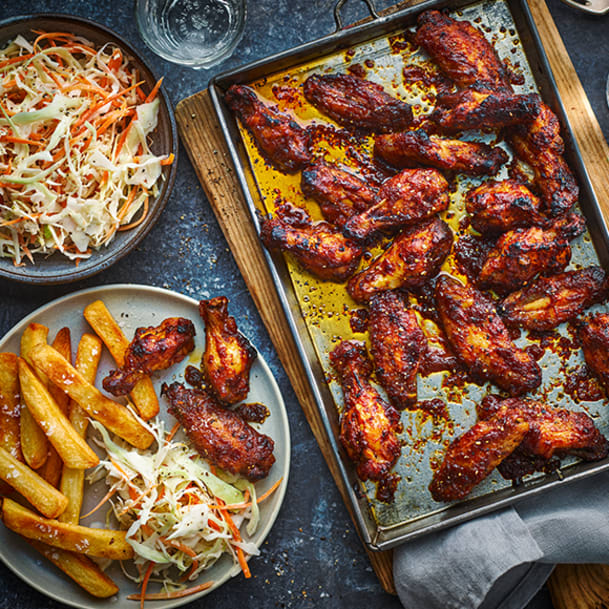 Full tray of hot honey chicken wings with a bowl of coleslaw