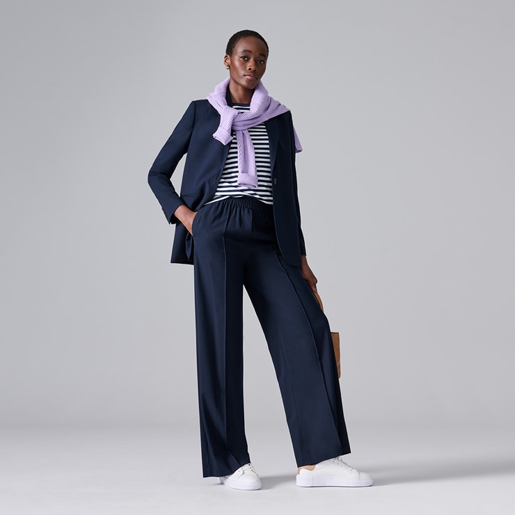 Woman wearing navy blue wide-leg suit and a stripy top. Shop workwear