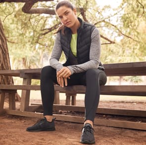 Woman wearing Goodmove trainers, leggings, long sleeved top and padded vest