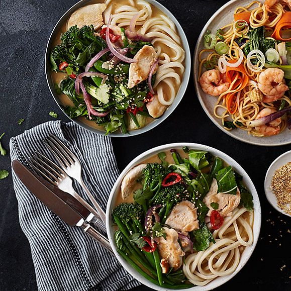 Bowls of chicken broth with noodles and stir-fried king prawns with noodles