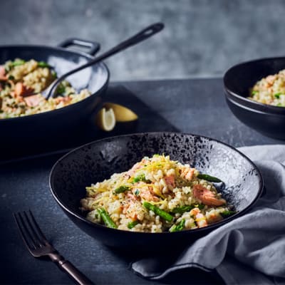 Salmon and asparagus risotto served in a black bowl