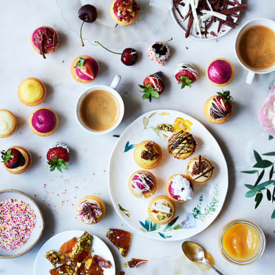 A tray of cupcakes with sweet toppings, fruit, lemon curd and sprinkles