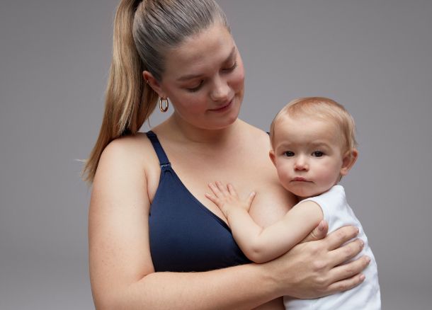 Woman wearing a nursing bra and holding baby. Book your nursing bra fit