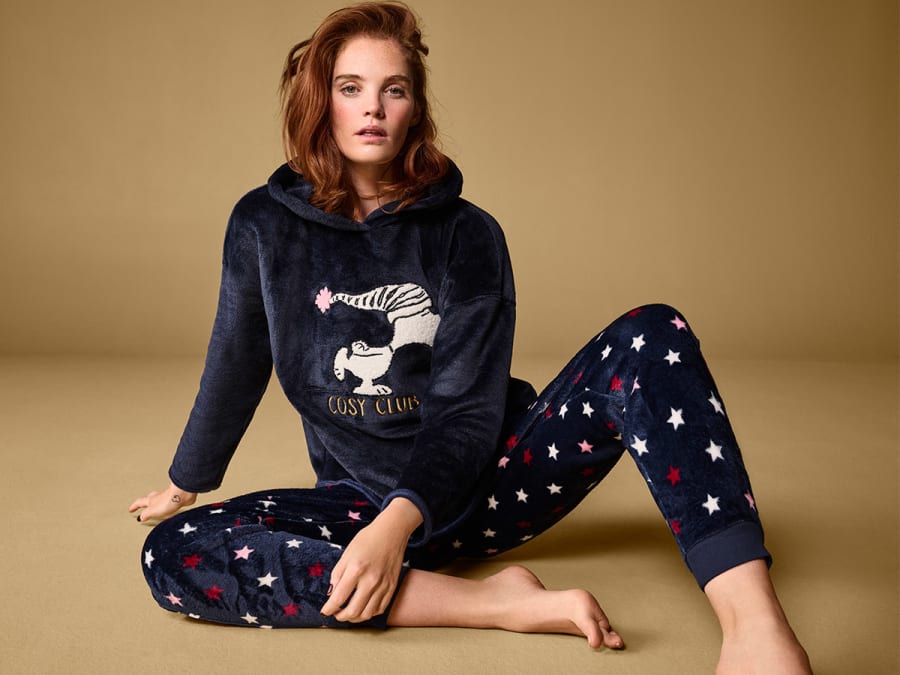 Woman wearing velour Snoopy pyjamas. Shop 20% off selected nightwear
