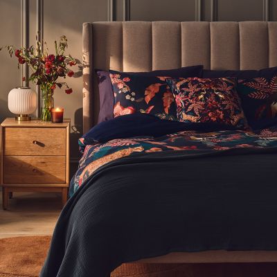 Bed made with floral duvet set, cushions and throw. Shop bedding