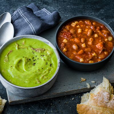 Pea and ham soup and minestrone soup served in bowls with crusty bread