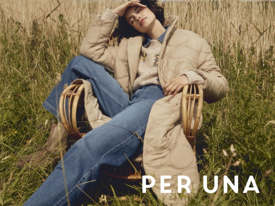 Woman wearing Per Una beige padded full-length coat, jeans and cream knitted jumper. Shop Per Una 