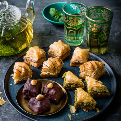 Selection of baklava on a tray with mint tea in a pot and glasses