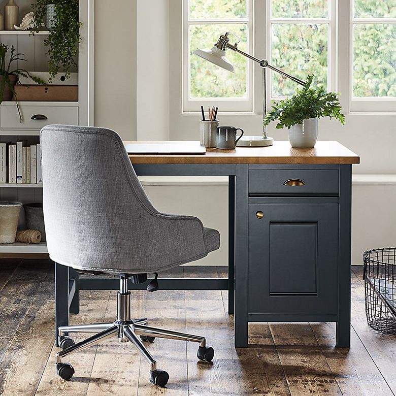 Home office with dark blue desk, grey office chair and off-white shelving