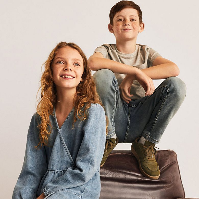 Girl wearing wrap denim dress and boy wearing grey T-shirt, jeans and khaki trainers