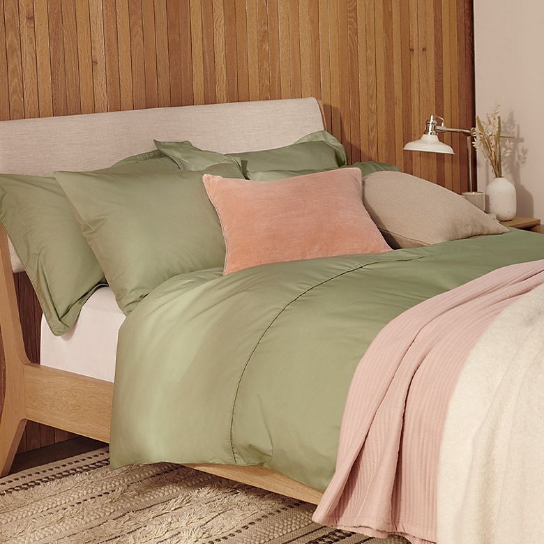 Bedroom with bed dressed in green, pink and cream bed linen