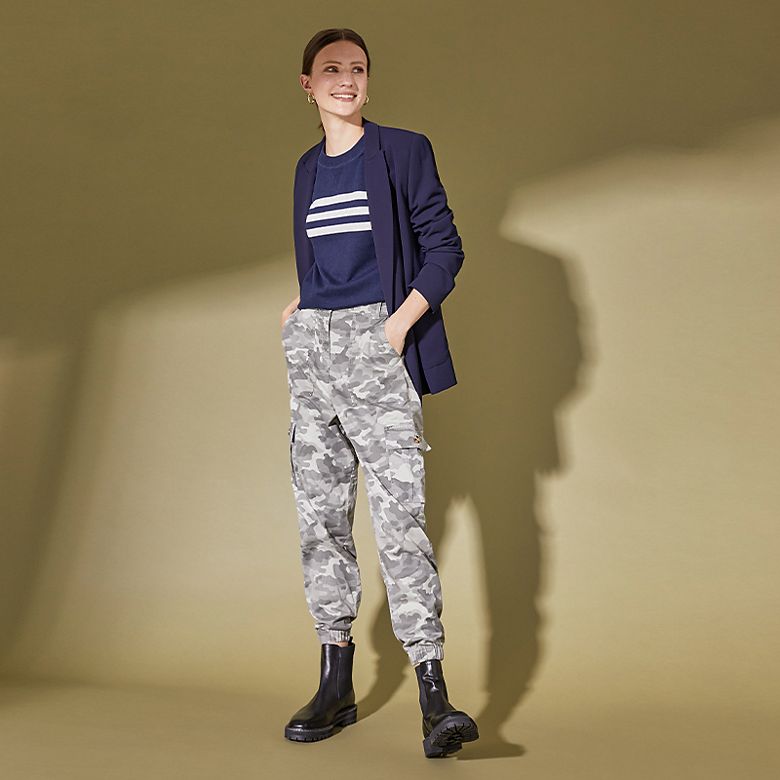 Woman wearing camo cargo pants with a navy stripe top, navy blazer and chunky boots 