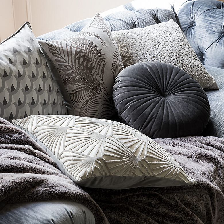 Sofa with pile of cushions and throws