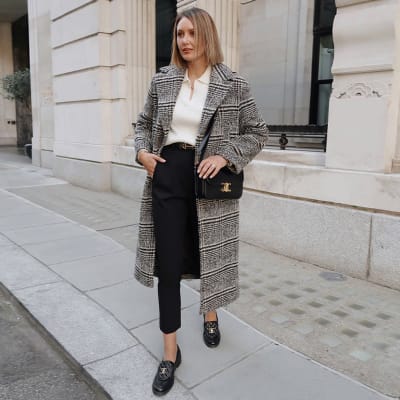 Woman wearing longline grey checked coat with black trousers