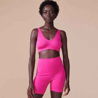 Woman wearing B by Boutique bright pink bralette and matching bright pink cycling shorts