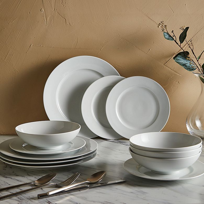 Selection of white plates and bowls and silver cutlery. Shop tableware