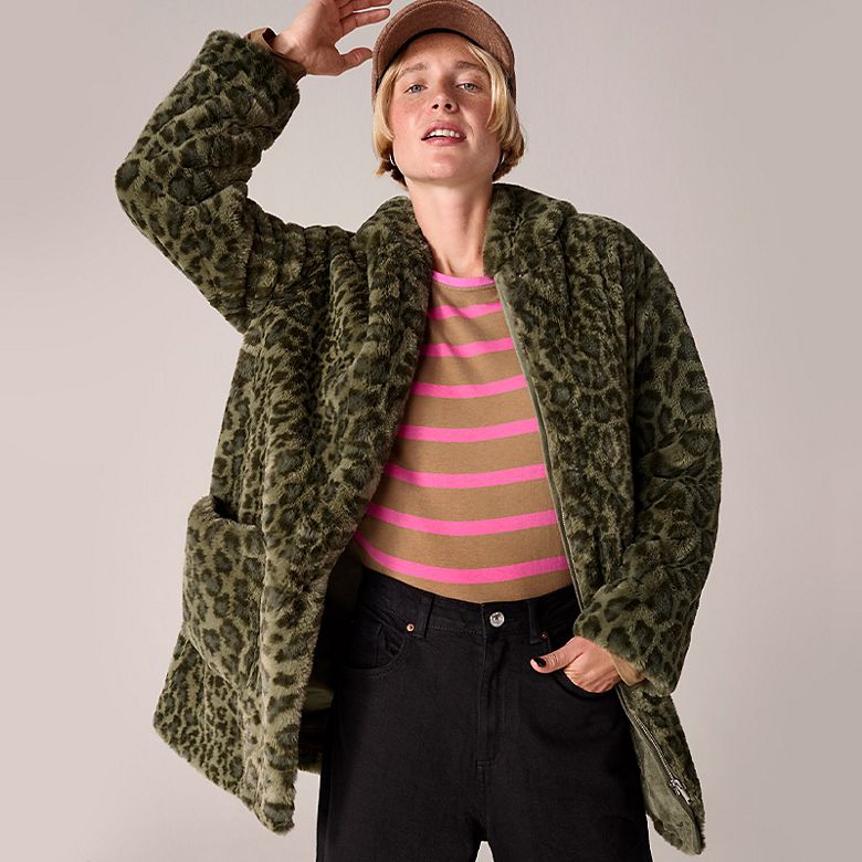 Woman wearing a striped T-shirt and green leopard-print coat. Shop women’s coats 