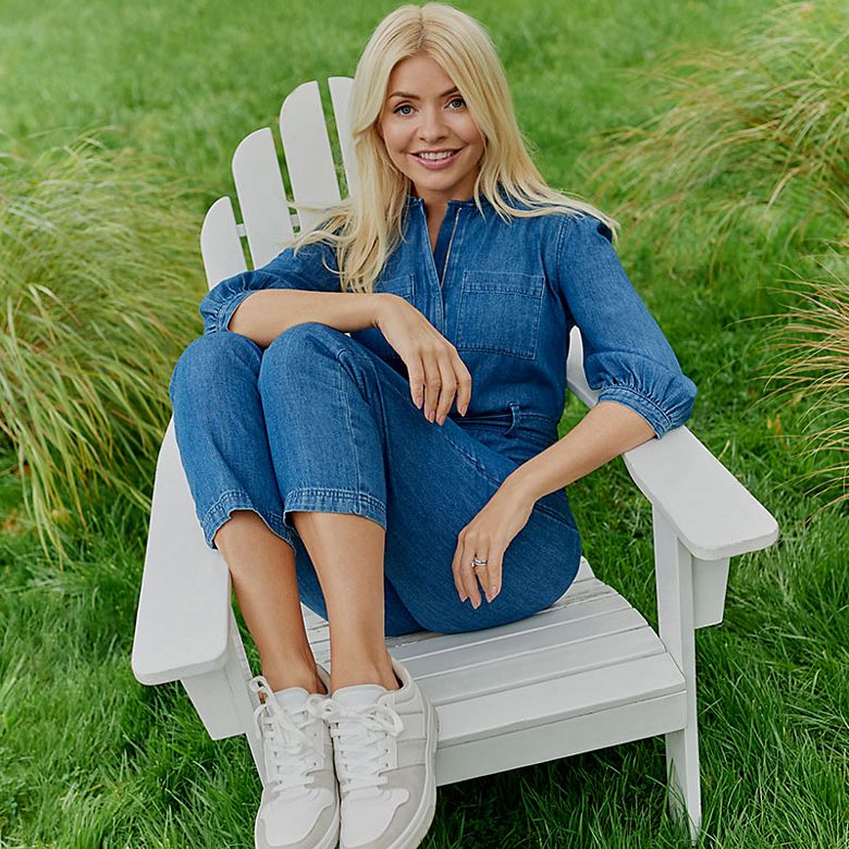 Holly Willoughby wearing blue denim jumpsuit and white trainers. Shop women’s new in