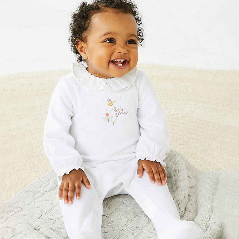 Baby wearing white babygrow with bee design. Shop  babygrows. 