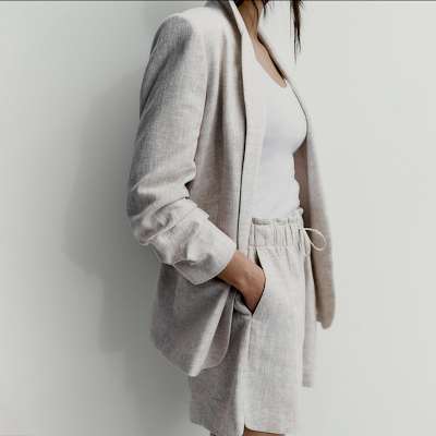 Woman wearing summer capsule wardrobe essentials including a linen suit. Shop capsule clothing