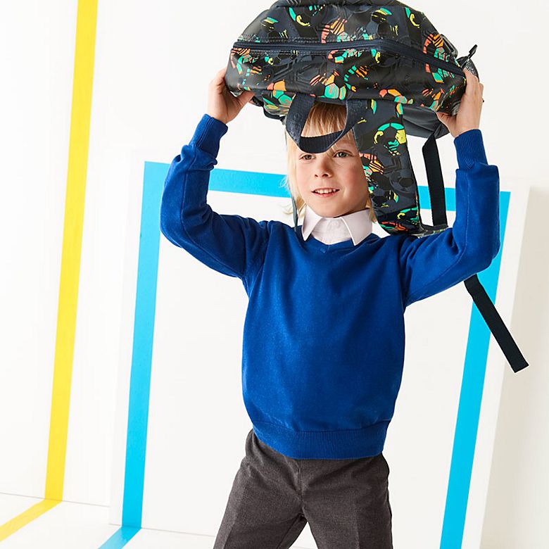 Boy wearing school uniform and carrying a backpack. Shop school bags