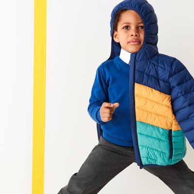 Boy wearing school uniform and a padded coat. Shop boys school uniform