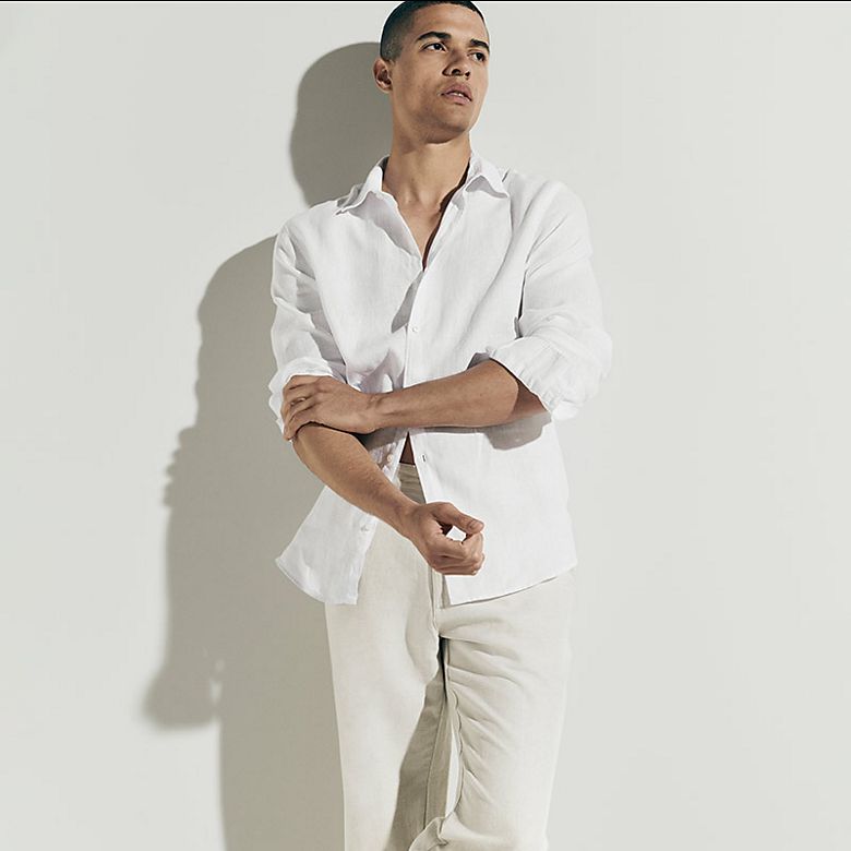 Man wearing summer capsule wardrobe essentials including a white shirt. Shop capsule clothing 