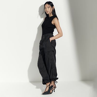 Woman wearing summer capsule wardrobe essentials including parachute trousers. Shop capsule clothing
