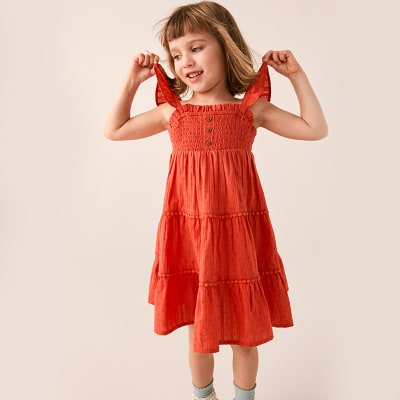 Girl wearing red cotton summer dress. Shop girls’ dresses.