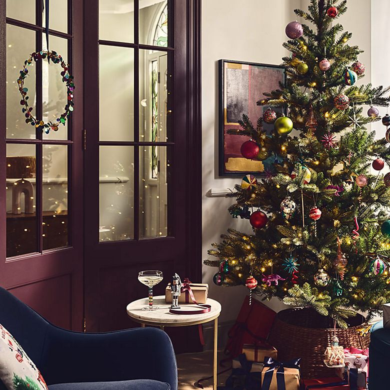 Room with a Christmas tree, festive wreath, decorations and presents. Shop Christmas decorations 
