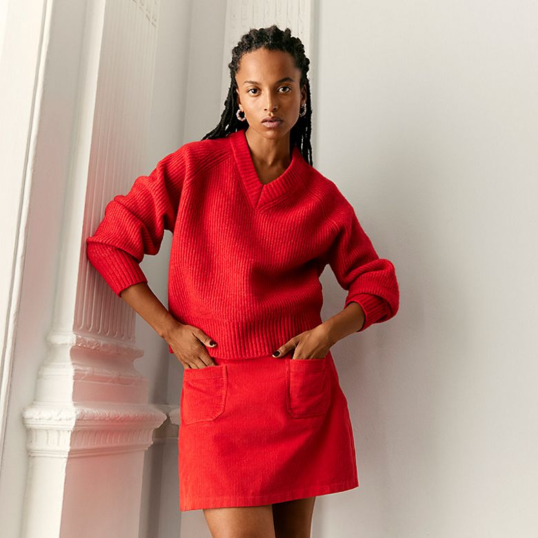 Woman wearing Nobody’s Child red jumper and mini skirt with pockets. Shop now