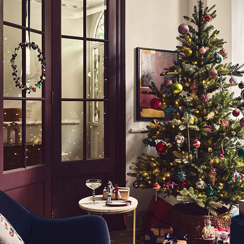 Room with a Christmas tree, festive wreath, decorations and presents. Shop Christmas decorations