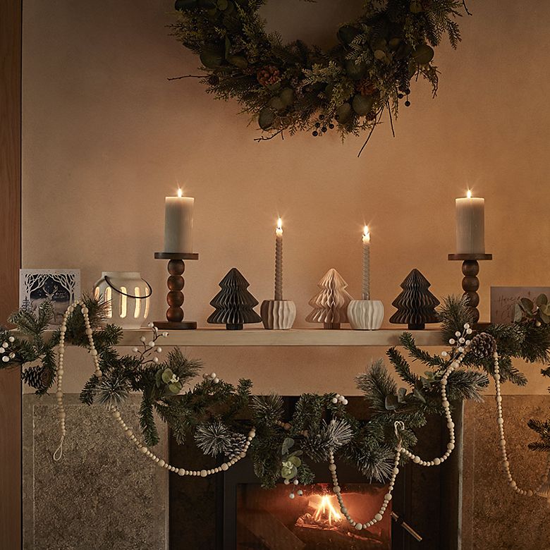 Mantlepiece decorated with candles, garlands and light-up candles. Shop Christmas wreaths