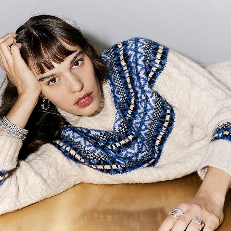 Woman wearing neutral-toned Fair Isle-patterned jumper. Shop women’s festive knitwear