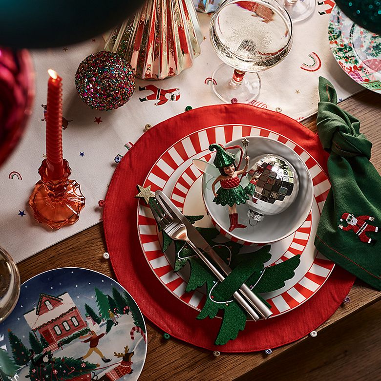 Christmas table set with red and white striped tableware and embroidered Christmas napkins. Shop Christmas tableware