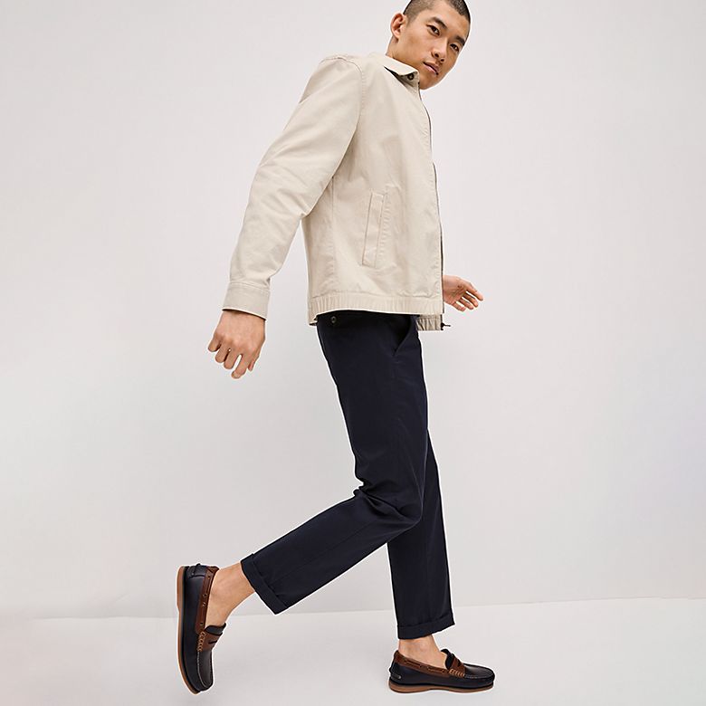 Man wearing navy regular-fit chinos, loafers and a cream jacket. Shop regular-fit chinos
