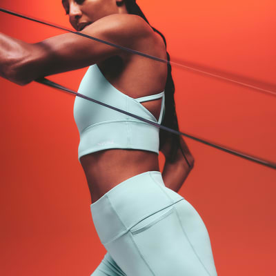 Woman wearing pale blue sports bra and matching leggings. Shop Puma