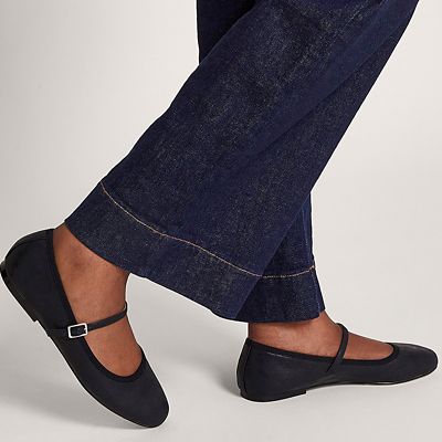 Woman wearing black mary janes and dark blue jeans. Shop women’s flat shoes