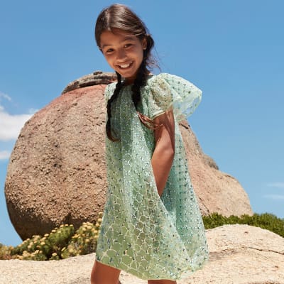 Girl wearing green embellished dress. Shop kids’ occasionwear