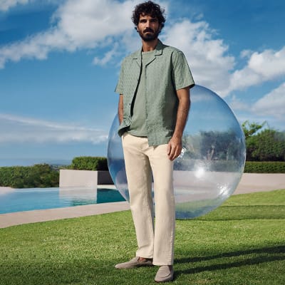 Man wearing sage-green short-sleeve shirt, sage-green T-shirt and cream jeans. Shop men’s shirts 