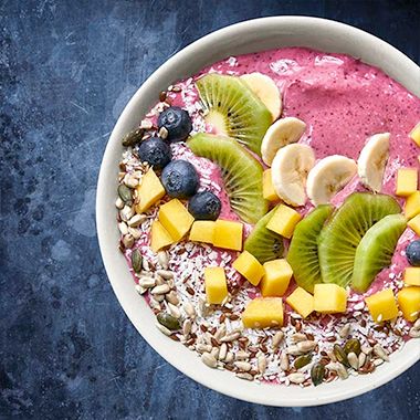 Bowl of kefir, seeds and mixed fruits on dark blue background